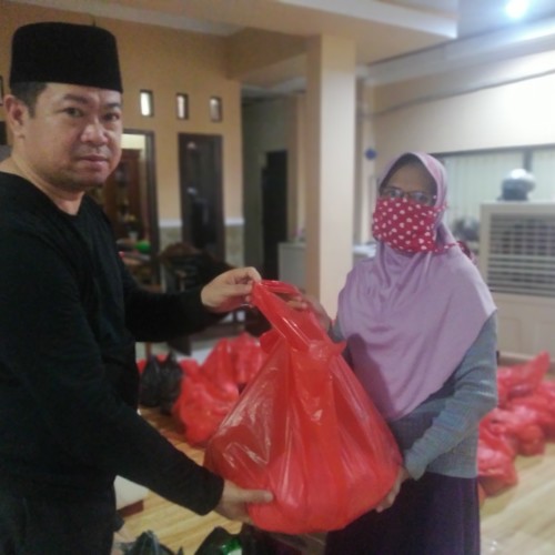Husen Saidan menyerahkan bantuan sembako kepada warga