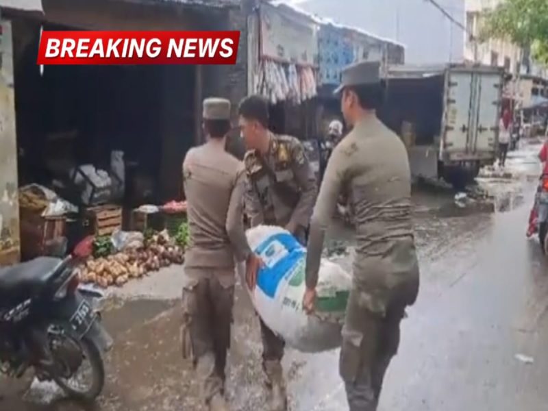 Tiga anggota Satpol PP mengangkut karung milik pedagang kaki lima saat penertiban di area pintu masuk Pasar Kranggot, Cilegon.