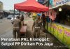 Dua petugas Satpol PP Cilegon berjaga di bawah tenda merah di trotoar Pasar Kranggot, berdiri di dekat warung minuman jus.